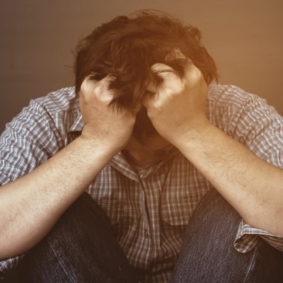 Man with his head down and his fists clenched in his hair